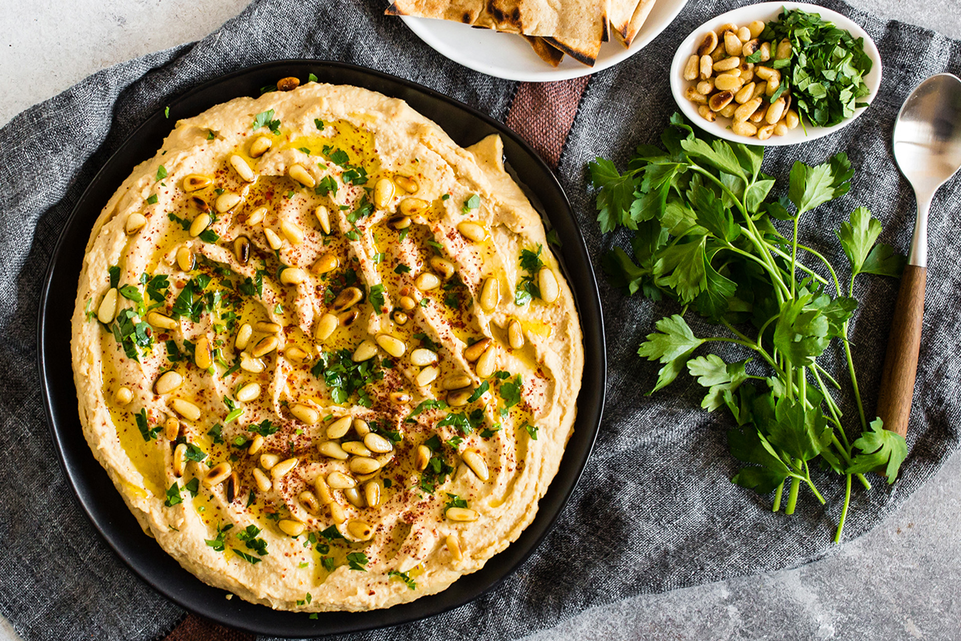 Hummus with pinenuts on top in a black bowl
