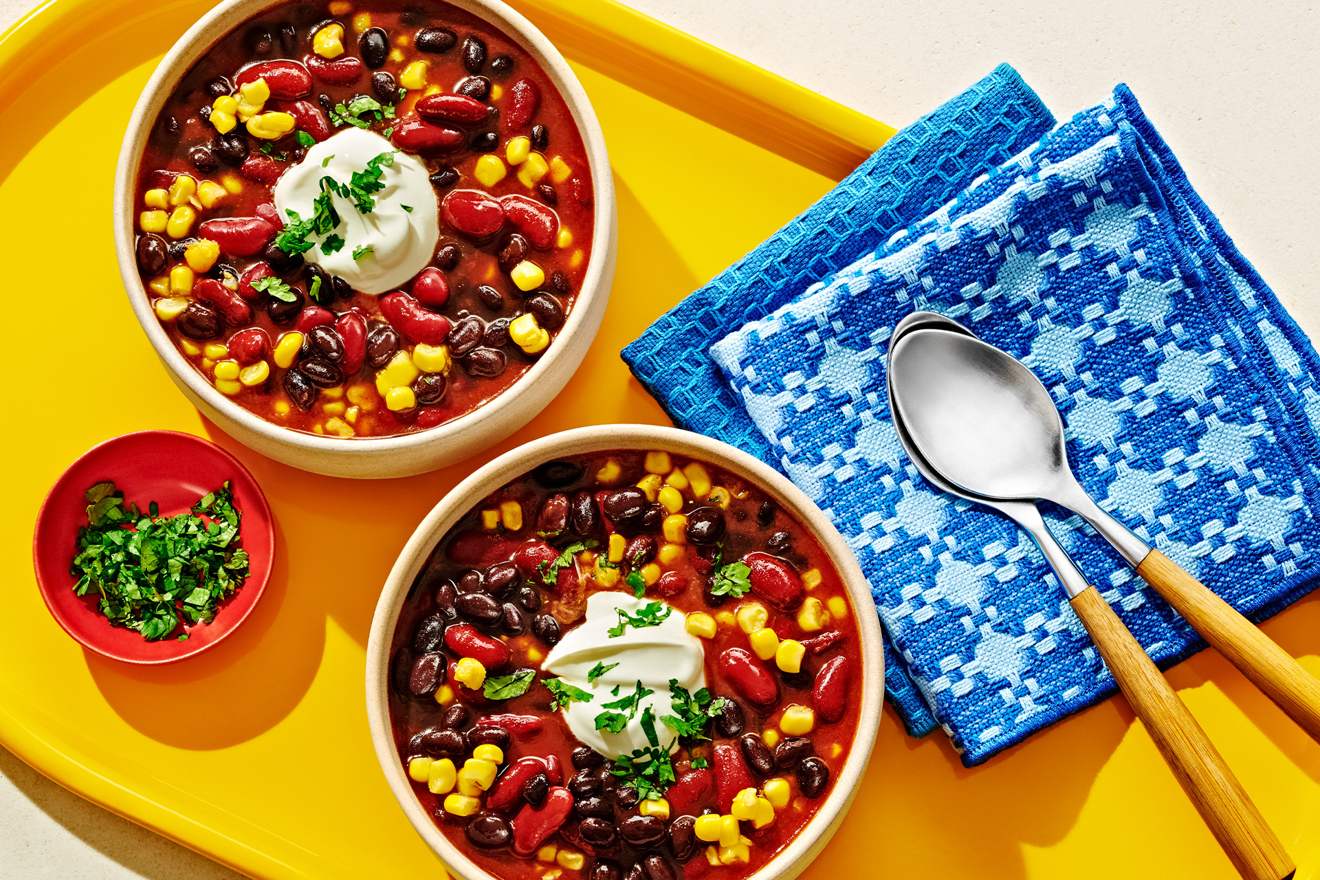 Bowl of chili with black beans, kidney beans, and corn topped with sour cream