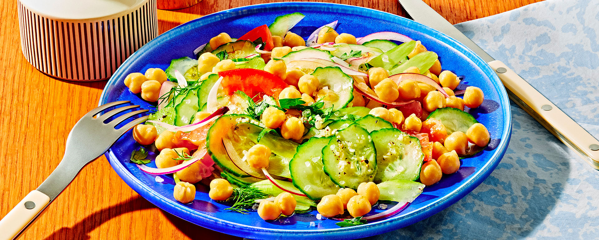 Cucumber and chickpea salad with citrus on a blue plate.