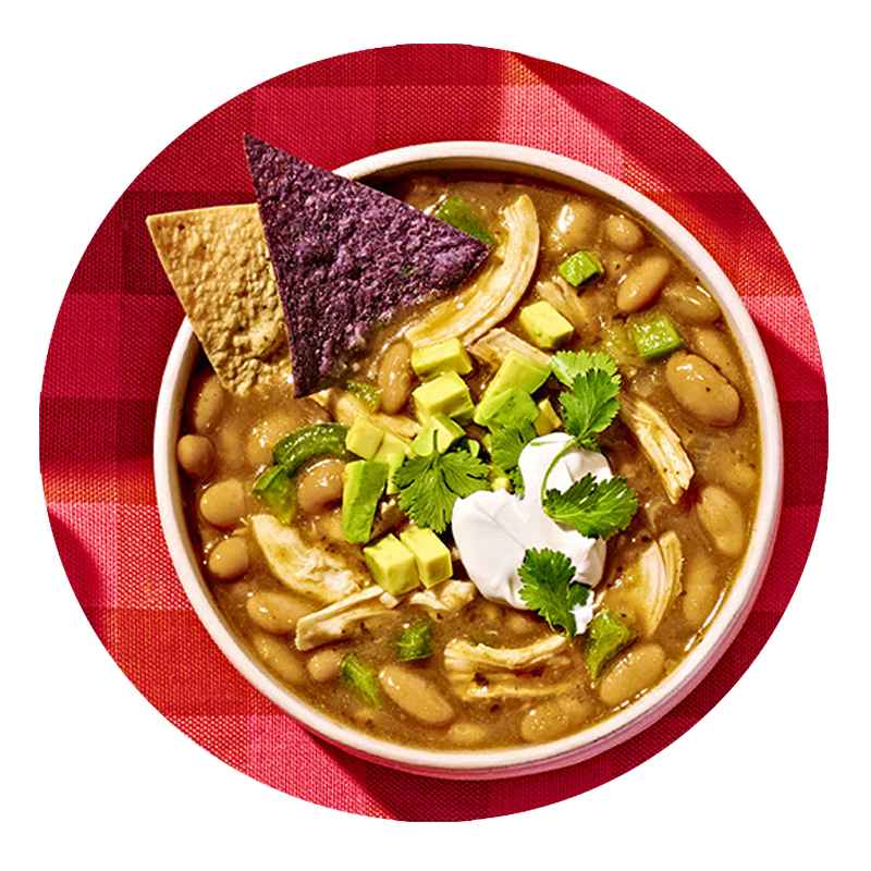 Bowl of white chicken chili made with Bush's Slow-Simmered White Chili Magic, sitting on a red tablecloth